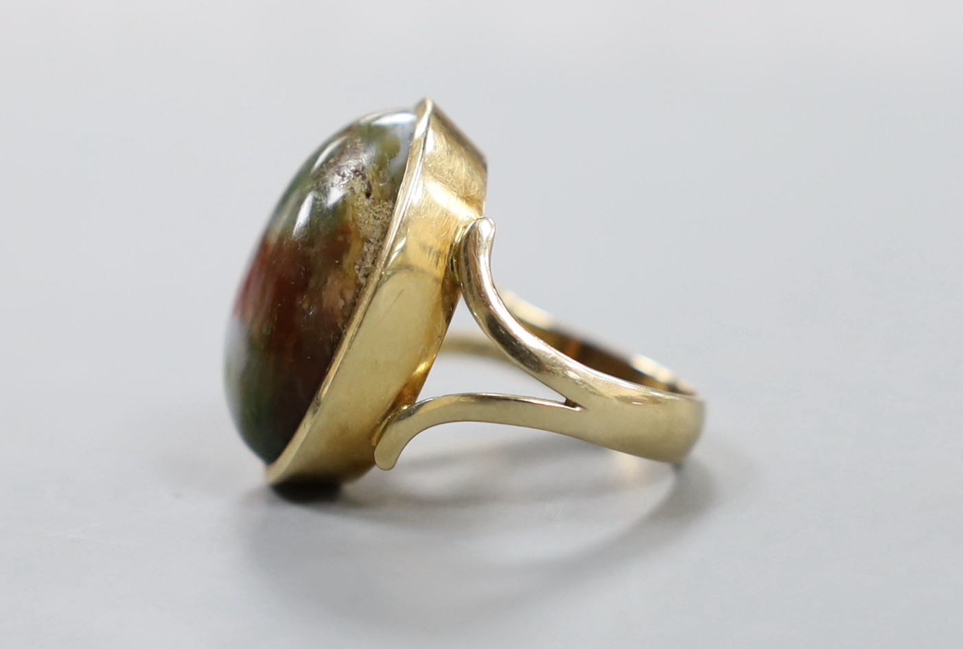 A yellow metal and cabochon polychrome agate? set oval ring, with engraved inscription to the shank, size O, gross weight 10.6 grams.